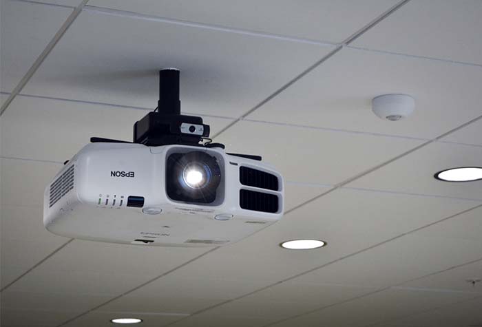 A projector mounted on an office ceiling