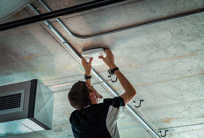 A Gamma Tech technician installing a ceiling wireless access point