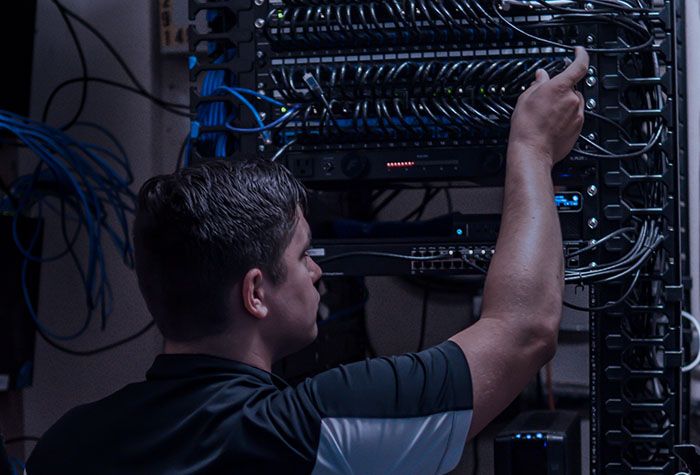A Gamma Tech technician working in a network rack