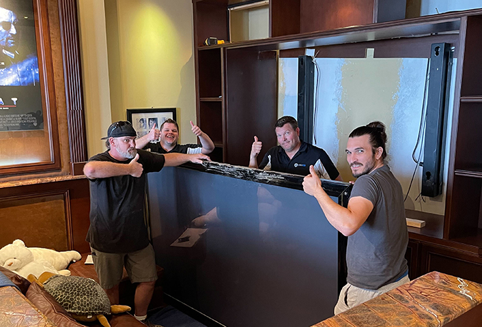 Gamma Tech Services team with thumbs up after removing a large residential TV