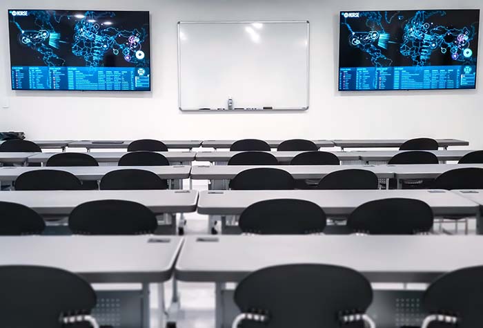 Gamma Tech Services classroom with TVs, whiteboard, and desks