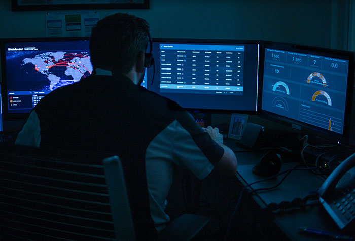 Gamma Tech cybersecurity technician looking at monitors